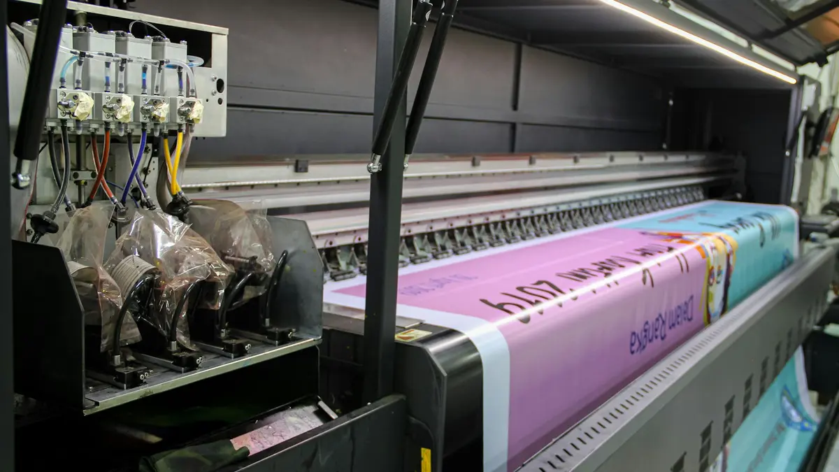 Close-up of textile printing equipment with large printed fabric roll in progress.